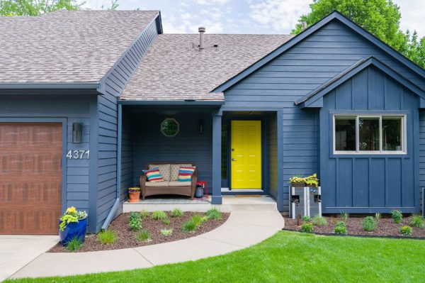 Home with new, blue siding and a bright yellow door.